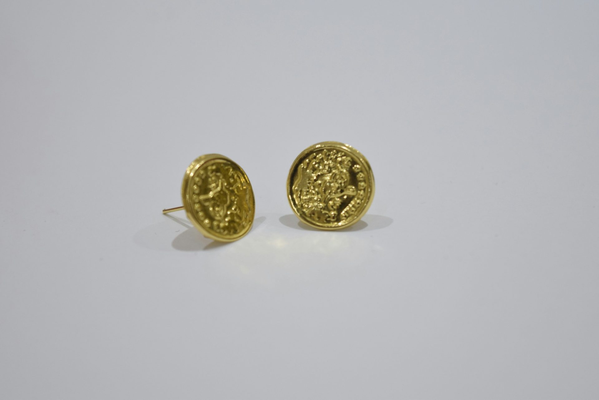 Two gold coin-shaped stud earrings on white background