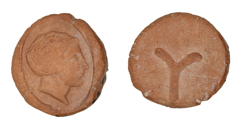 Ancient terracotta token with a worn figurative relief on one side and a partially preserved linear symbol on the other.